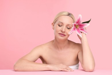 Photo of Beautiful woman with lily flower on light pink background