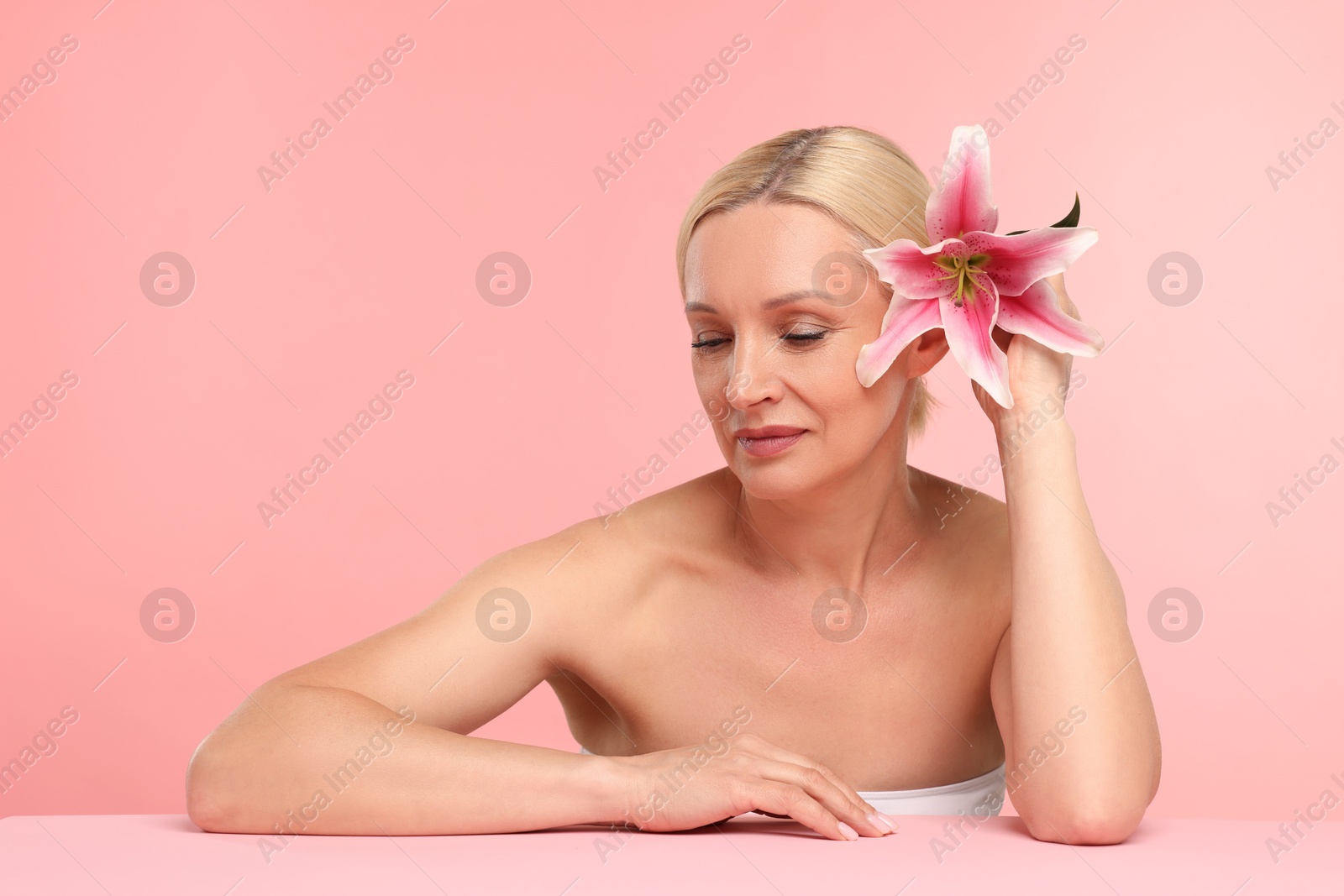 Beautiful woman with lily flower on light pink background. Space for text Photo of Beautiful woman with lily flower on light pink background. Space for text