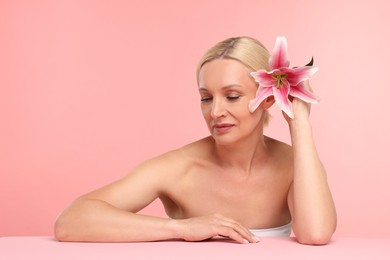 Photo of Beautiful woman with lily flower on light pink background. Space for text