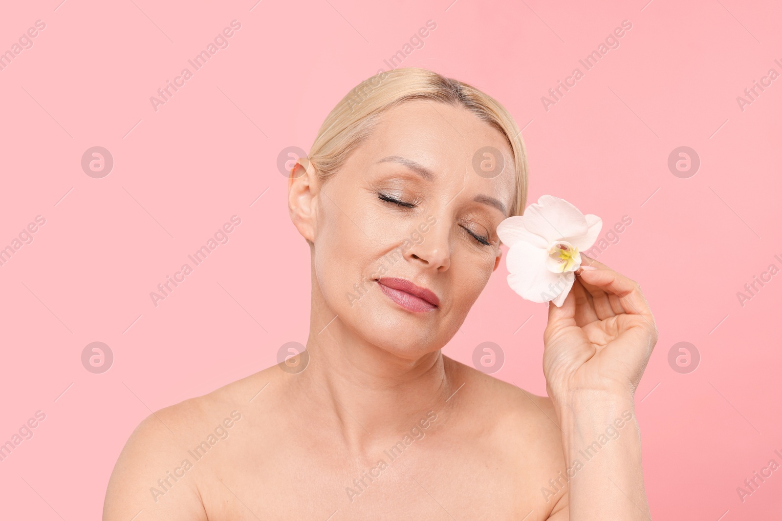 Beautiful woman with orchid flower on light pink background Photo of Beautiful woman with orchid flower on light pink background