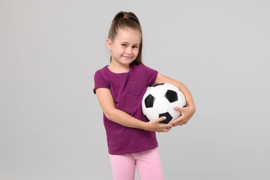 Photo of Little girl with soccer ball on light grey background