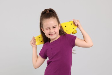 Photo of Little girl with penny board on light grey background