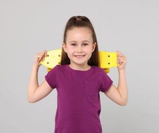 Photo of Little girl with penny board on light grey background