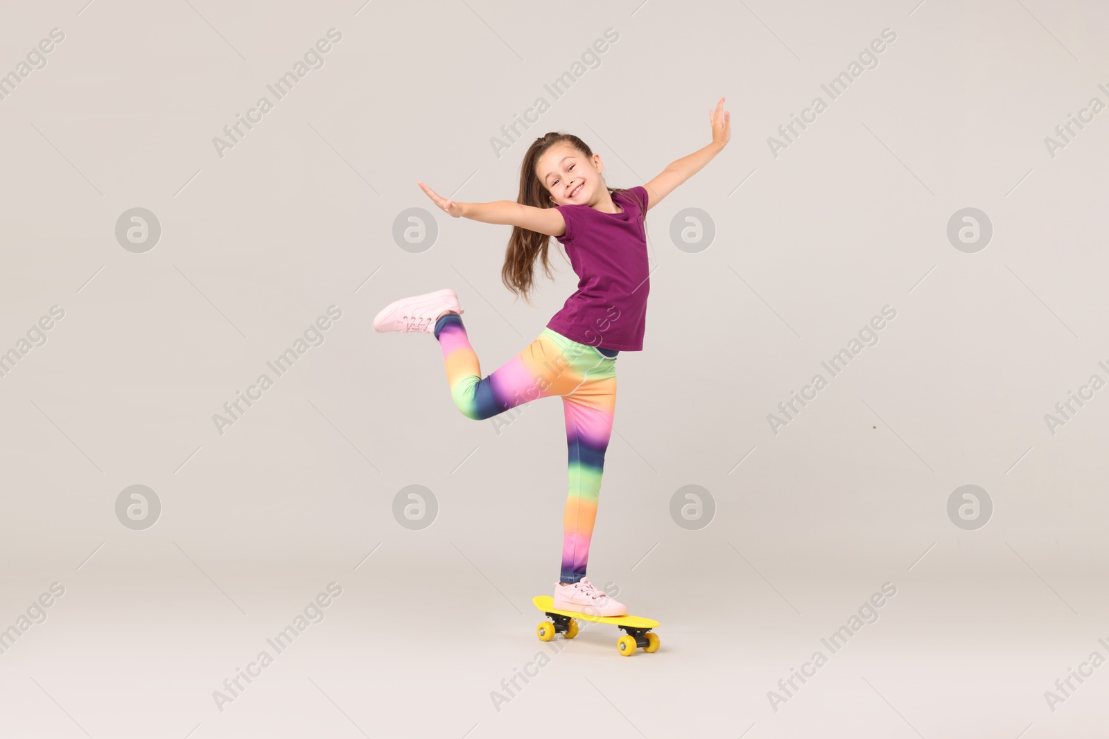 Little girl with penny board on light grey background Photo of Little girl with penny board on light grey background