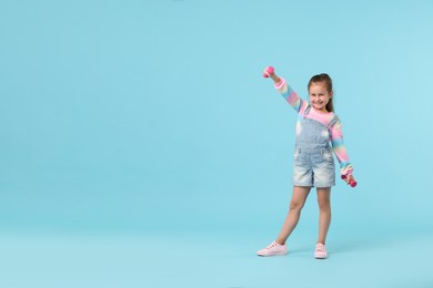 Photo of Little girl with dumbbells on light blue background, space for text