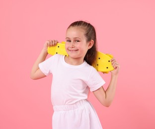 Photo of Little girl with penny board on pink background