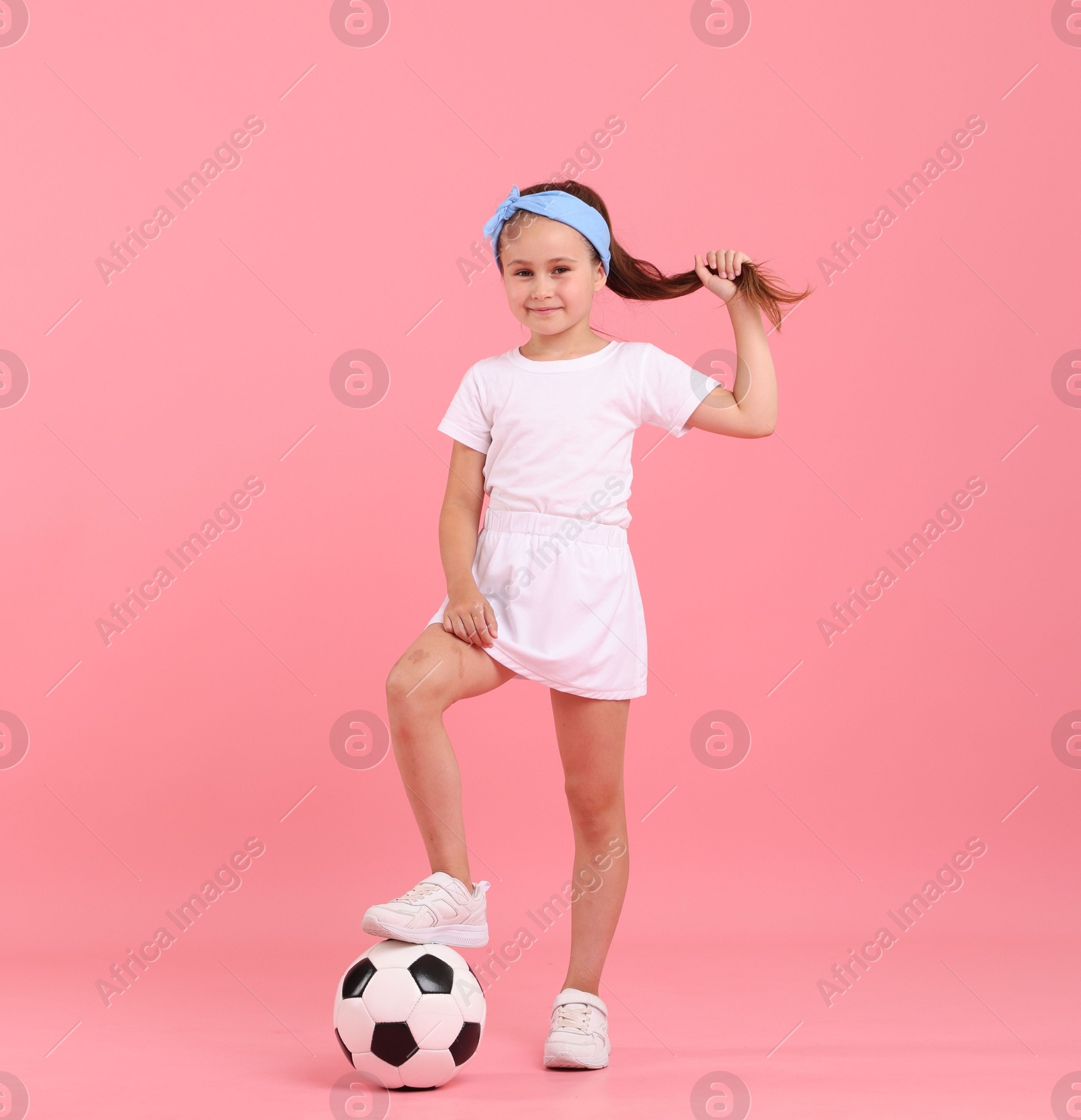 Little girl with soccer ball on pink background Photo of Little girl with soccer ball on pink background