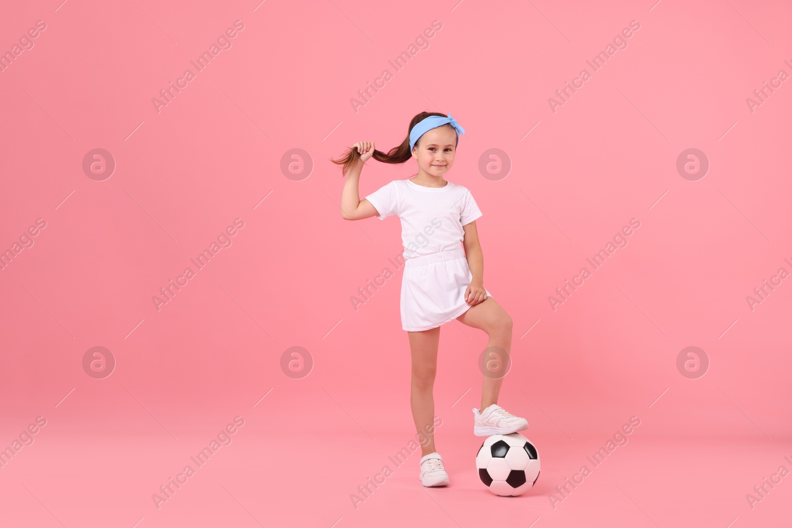 Little girl with soccer ball on pink background Photo of Little girl with soccer ball on pink background