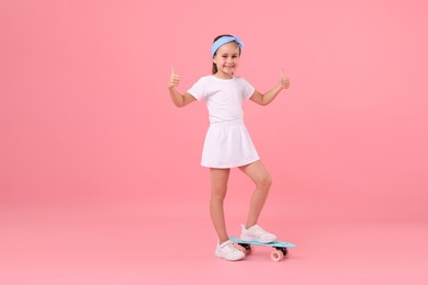 Photo of Little girl with penny board on pink background