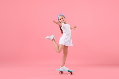 Photo of Little girl with penny board on pink background