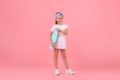 Photo of Little girl with penny board on pink background