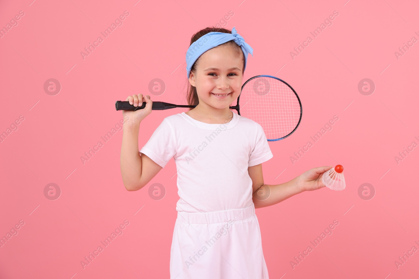 Little girl with tennis racket and shuttlecock on pink background Photo of Little girl with tennis racket and shuttlecock on pink background