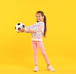 Photo of Little girl with soccer ball on yellow background