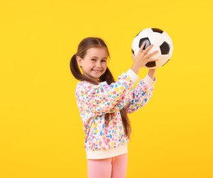 Photo of Little girl with soccer ball on yellow background