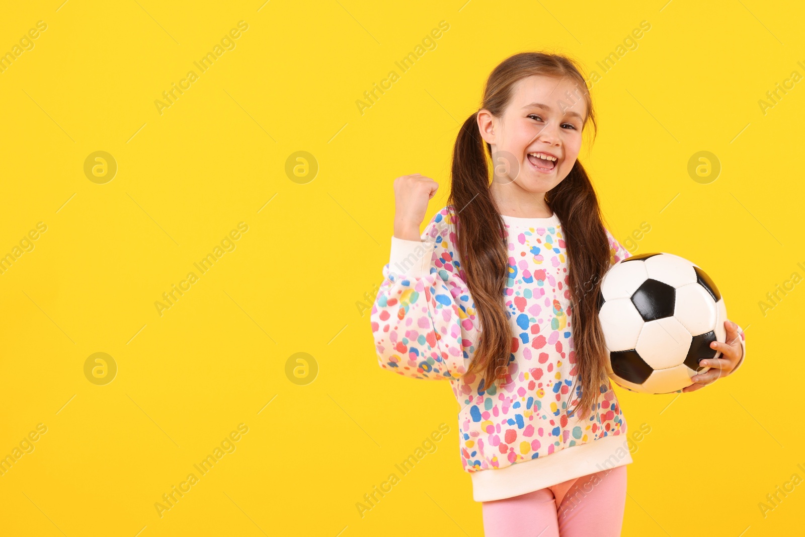 Little girl with soccer ball on yellow background, space for text Photo of Little girl with soccer ball on yellow background, space for text