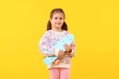 Photo of Little girl with penny board on yellow background