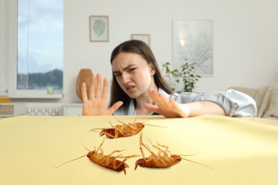 Image of Emotional young woman looking in disgust at cockroaches on table indoors, selective focus