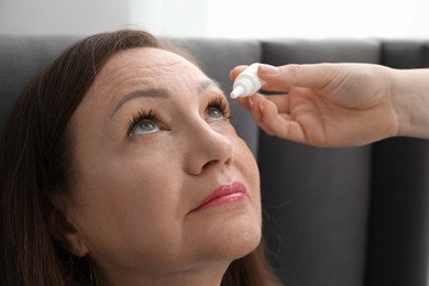Photo of Daughter dripping medication into mother's eye at home, closeup