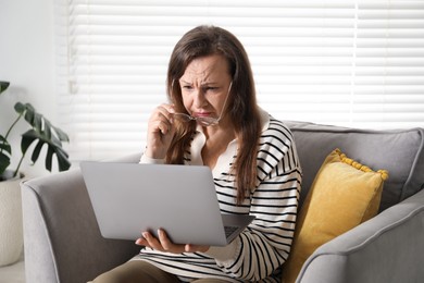 Photo of Woman with vision problem using laptop in armchair at home
