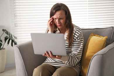 Photo of Woman with vision problem using laptop in armchair at home