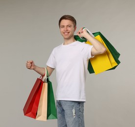 Photo of Cheerful man with shopping bags on light grey background