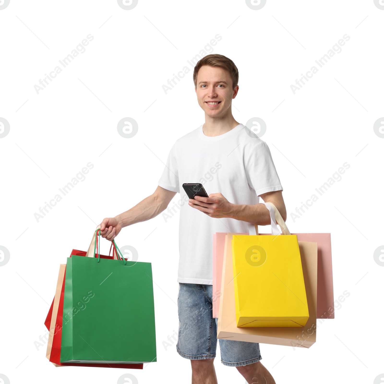 Cheerful man with smartphone and shopping bags on white background Photo of Cheerful man with smartphone and shopping bags on white background