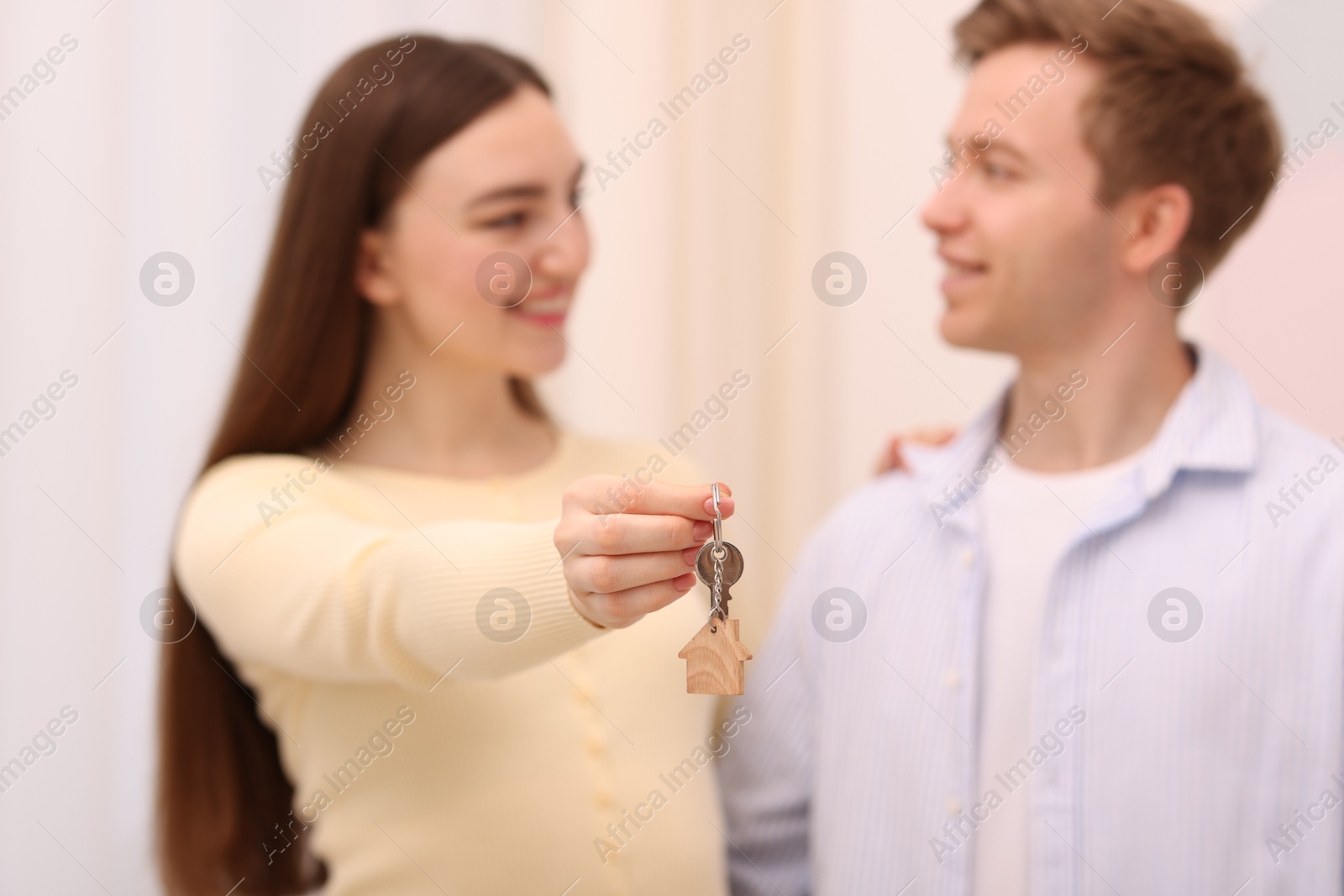 Happy couple with key of their new house indoors, selective focus Photo of Happy couple with key of their new house indoors, selective focus