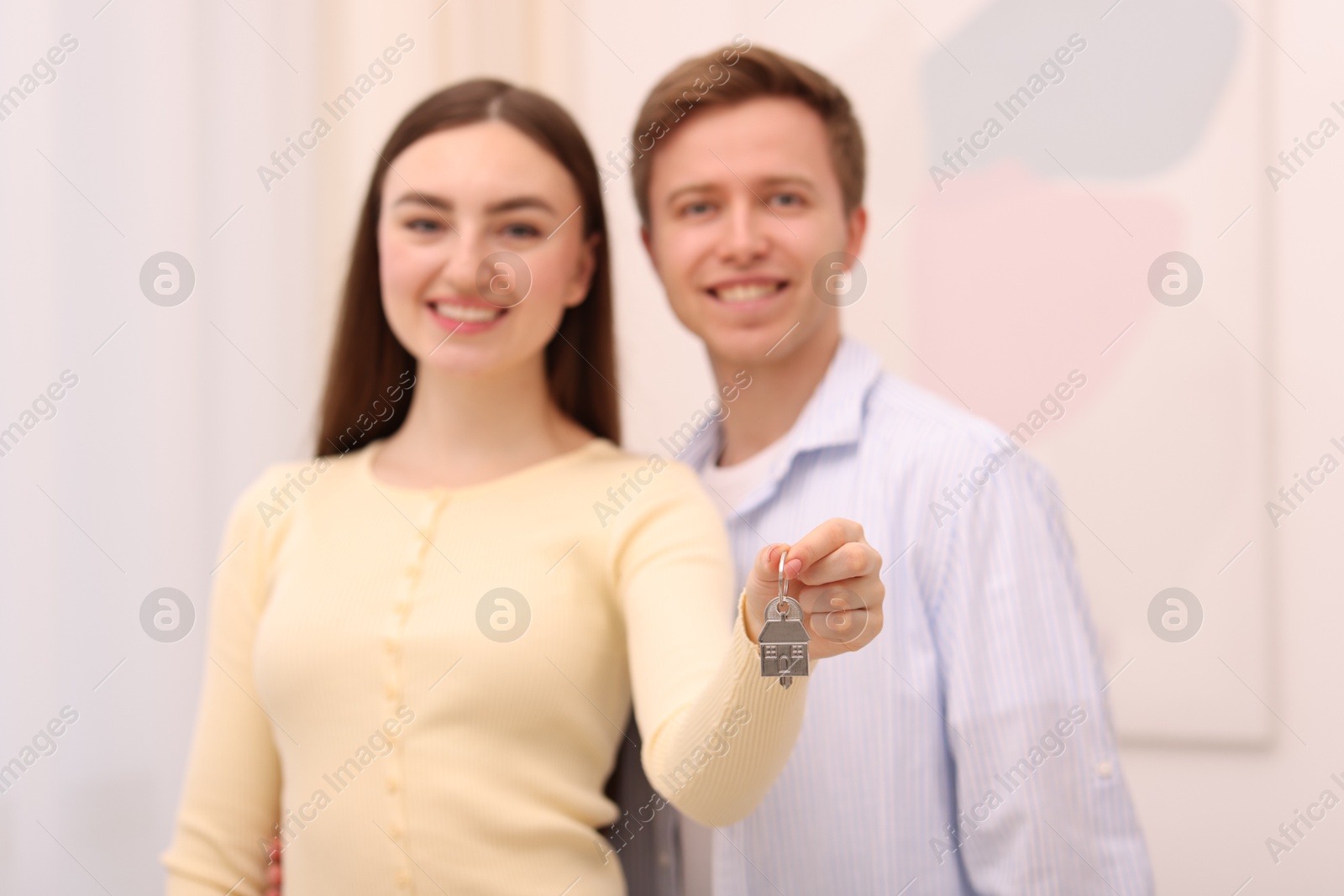 Happy couple with key of their new house indoors, selective focus Photo of Happy couple with key of their new house indoors, selective focus