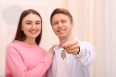 Photo of Happy couple with key of their new apartment indoors, selective focus