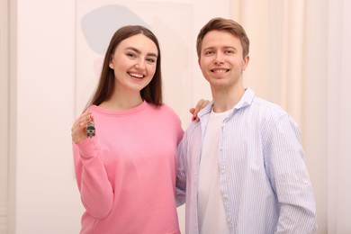 Photo of Happy couple with key of their new apartment indoors