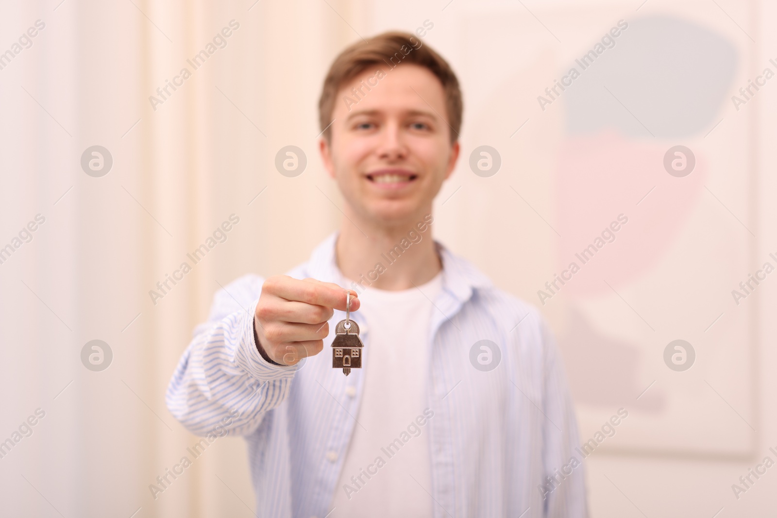 Happy man with house keys indoors, selective focus Photo of Happy man with house keys indoors, selective focus