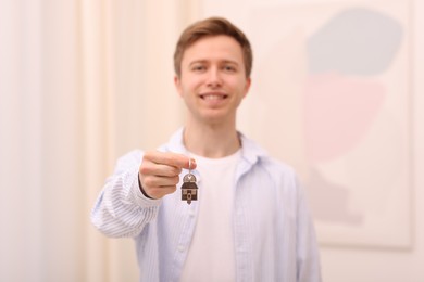 Photo of Happy man with house keys indoors, selective focus