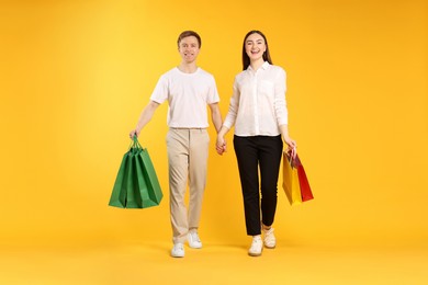 Photo of Happy couple with shopping bags on yellow background