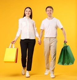 Photo of Happy couple with shopping bags on yellow background