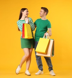 Photo of Happy couple with shopping bags on yellow background