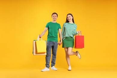 Photo of Happy couple with shopping bags on yellow background
