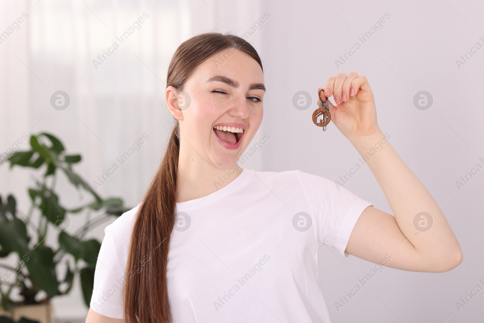 Happy woman with key of her new house indoors Photo of Happy woman with key of her new house indoors