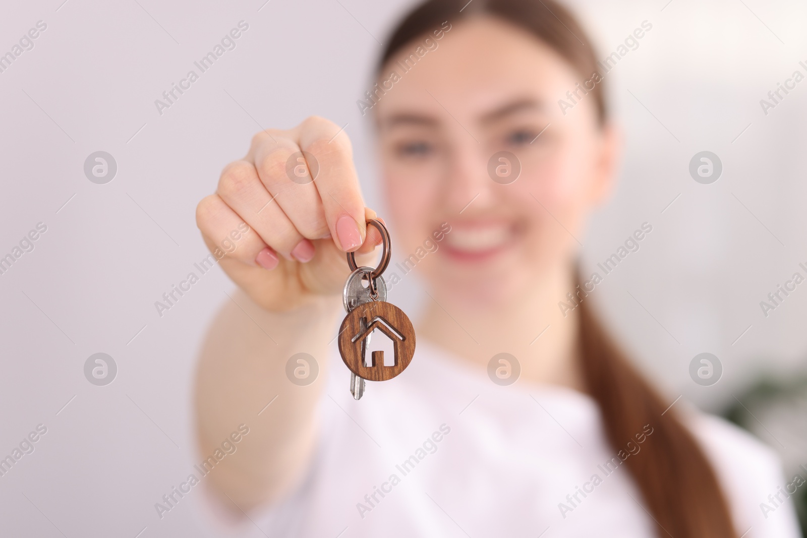 Happy woman with key of her new house indoors, selective focus Photo of Happy woman with key of her new house indoors, selective focus