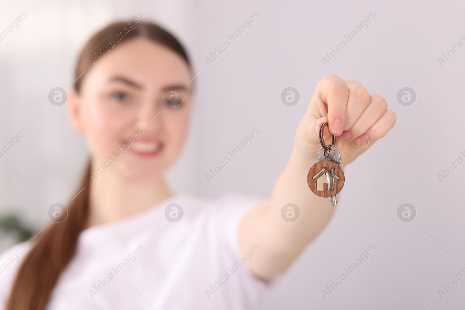 Happy woman with key of her new house indoors, selective focus Photo of Happy woman with key of her new house indoors, selective focus