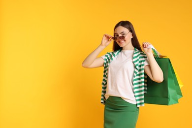 Photo of Positive woman with shopping bags on yellow background. Space for text