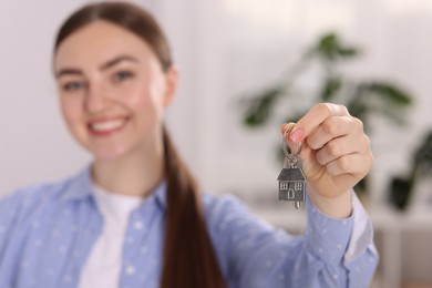 Photo of Happy woman with key of her new apartment indoors, selective focus