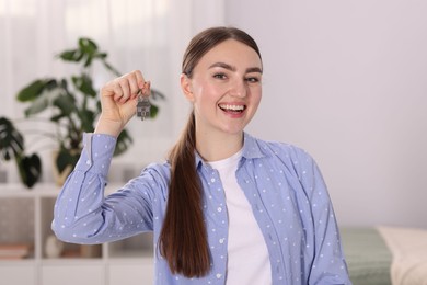 Photo of Happy woman with key of her new apartment indoors