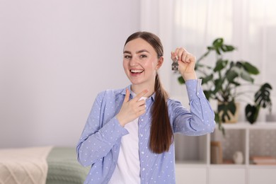 Photo of Happy woman with key of her new apartment indoors
