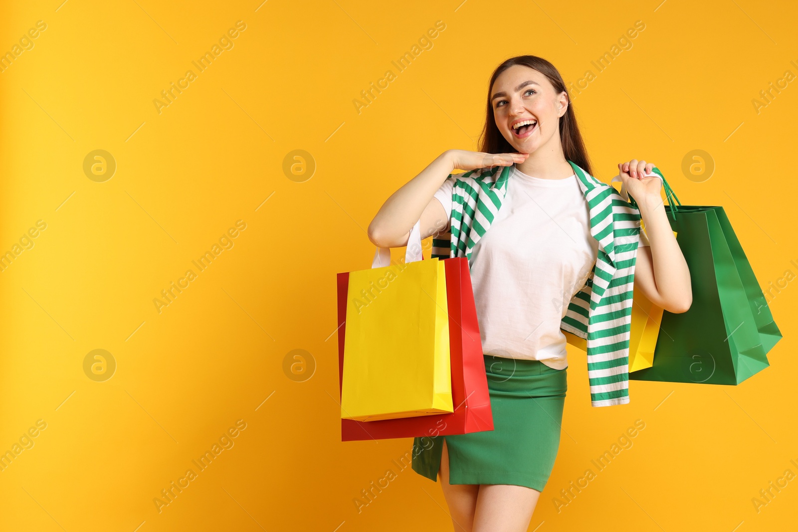 Excited woman with shopping bags on yellow background. Space for text Photo of Excited woman with shopping bags on yellow background. Space for text