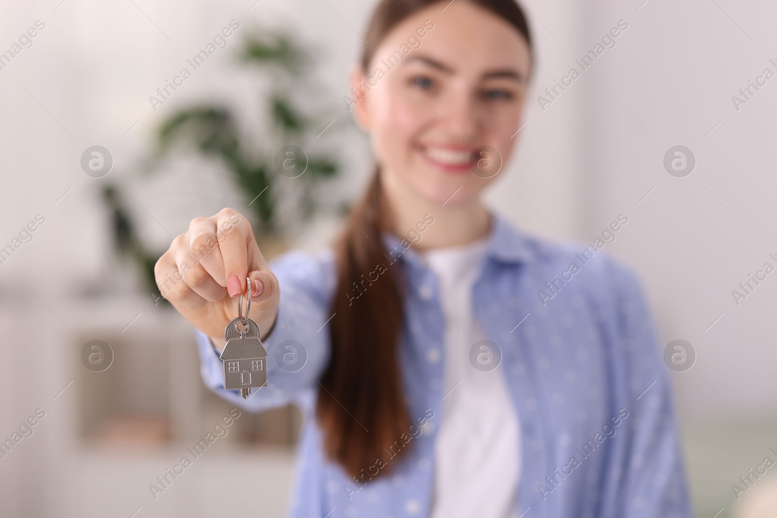 Photo of Happy woman with key of her new apartment indoors, selective focus