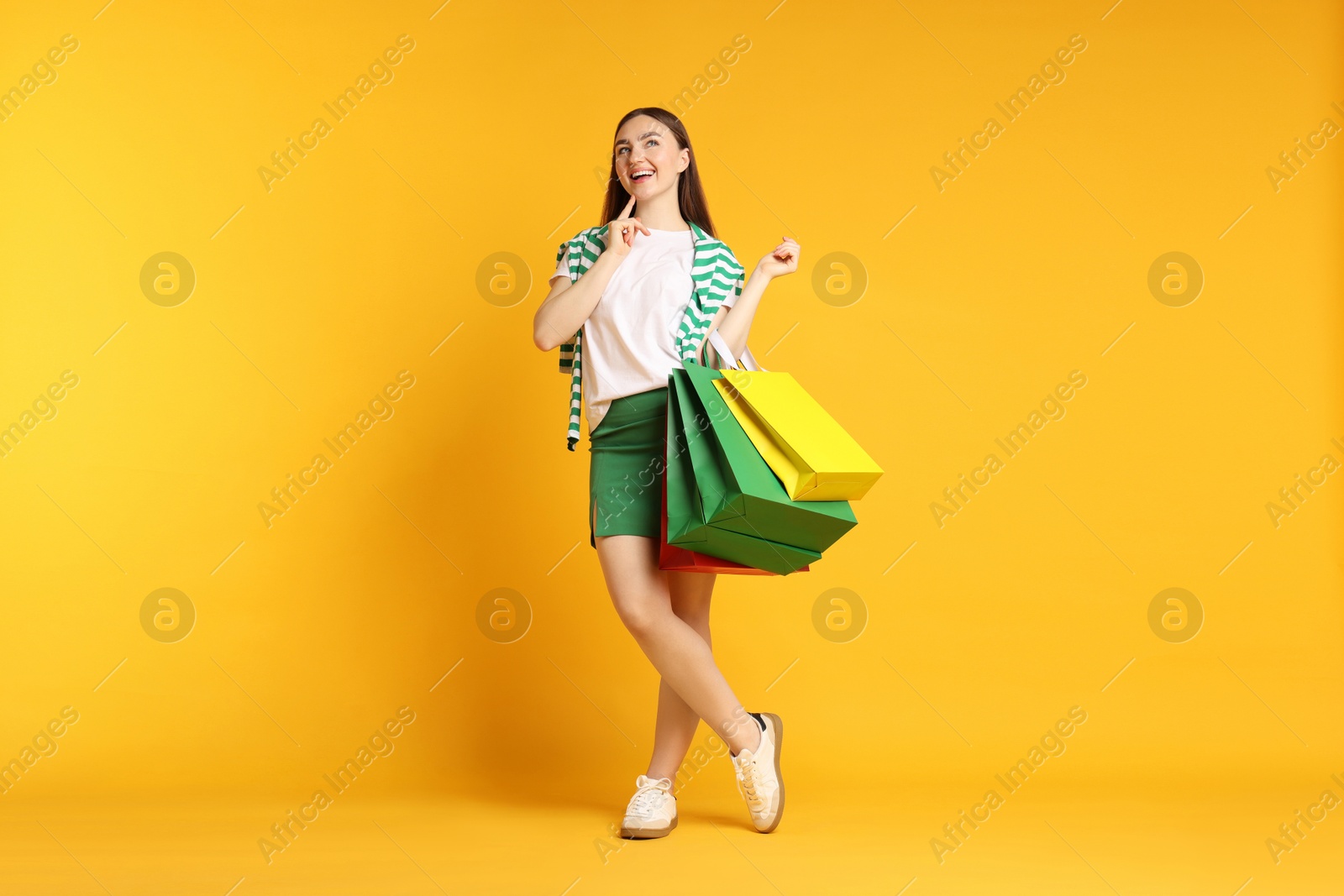 Positive woman with shopping bags on yellow background Photo of Positive woman with shopping bags on yellow background