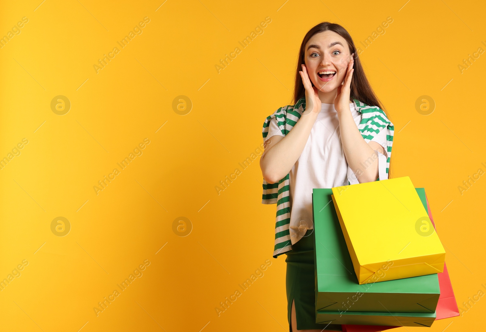 Excited woman with shopping bags on yellow background. Space for text Photo of Excited woman with shopping bags on yellow background. Space for text