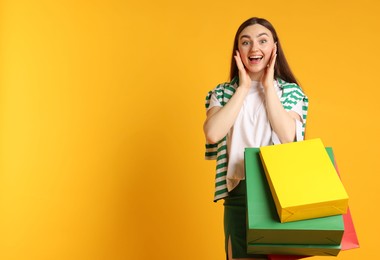 Photo of Excited woman with shopping bags on yellow background. Space for text