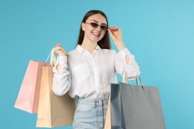 Photo of Positive woman with shopping bags on light blue background