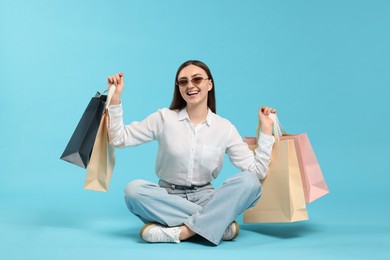 Photo of Excited woman with shopping bags on light blue background